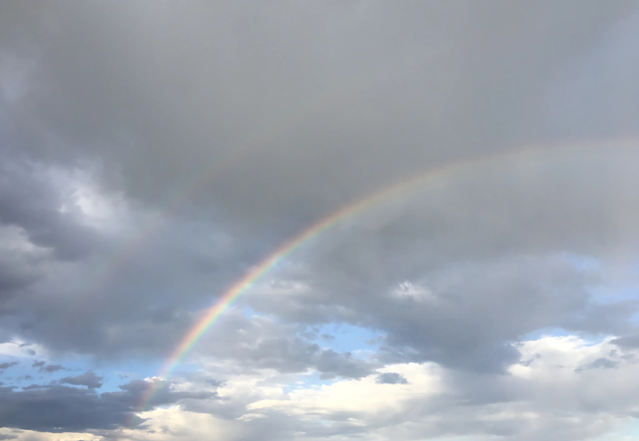 Photo of a double rainbow in a cloudy sky